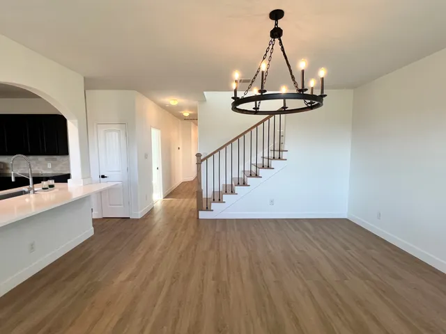 a view of a room with wooden floor a ceiling fan and a kitchen view