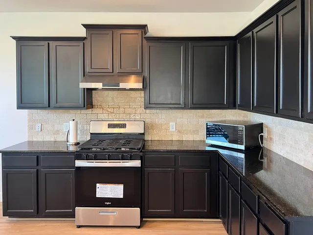 a kitchen with granite countertop a stove a sink and cabinets