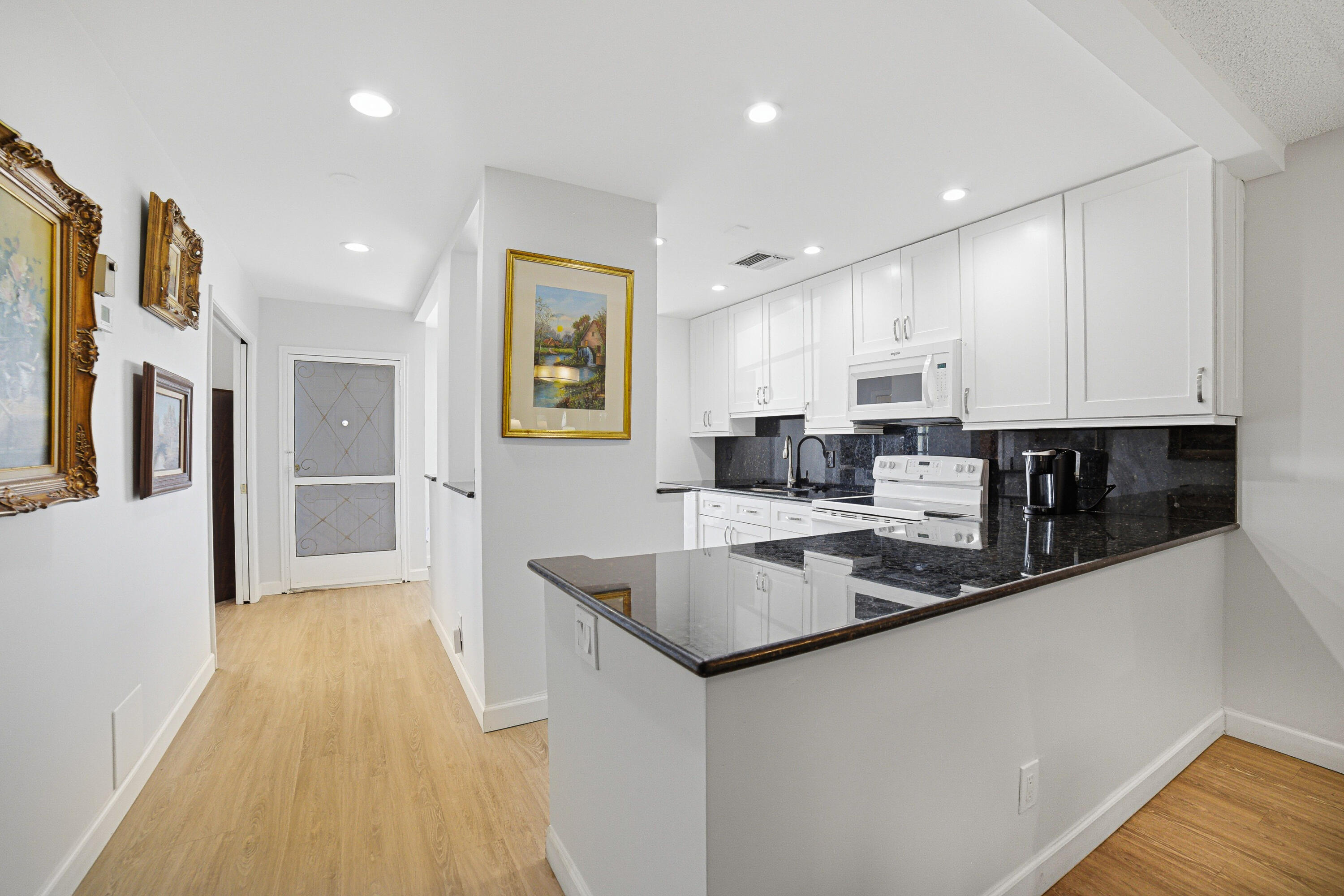 2901 Southwest 15th Street, Unit 102 Delray Beach, FL 33445 - Photo 6 of 59 a kitchen with stainless steel appliances granite countertop a refrigerator a stove and a sink with wooden floor
