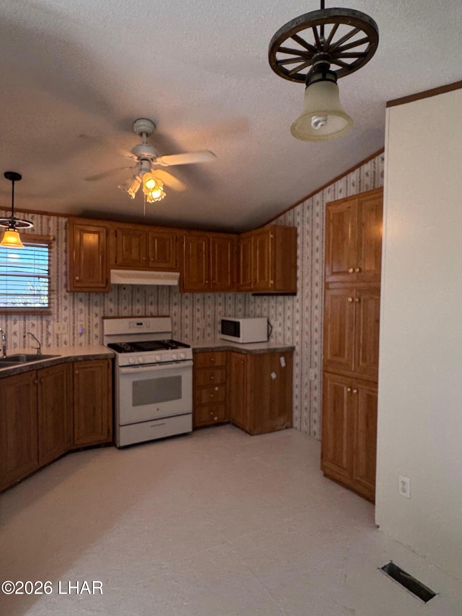 15454 Mohave Road Yucca, AZ 86438 - Photo 13 of 47 a kitchen with stainless steel appliances a refrigerator a stove a sink dishwasher a oven with wooden cabinets and floor