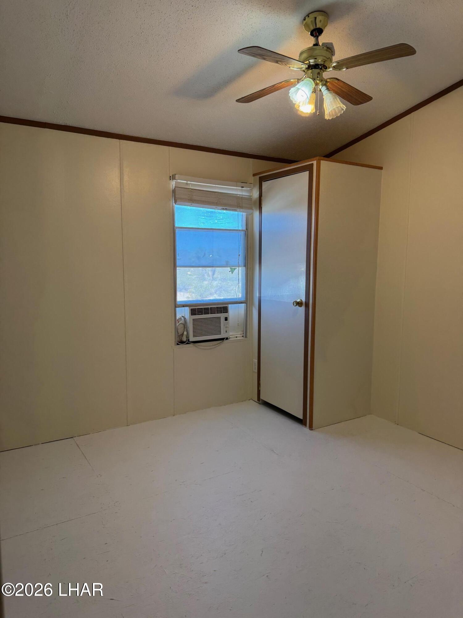 15454 Mohave Road Yucca, AZ 86438 - Photo 21 of 47 a view of a big room with wooden floor closet ceiling fan and windows