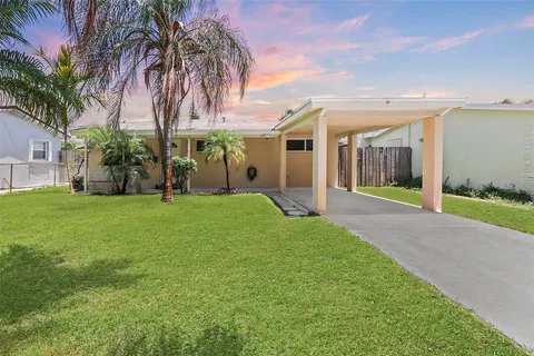 a view of a house with a yard and palm trees