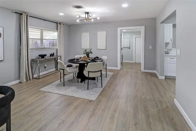 a living room with furniture a dining table wooden floor and a large window