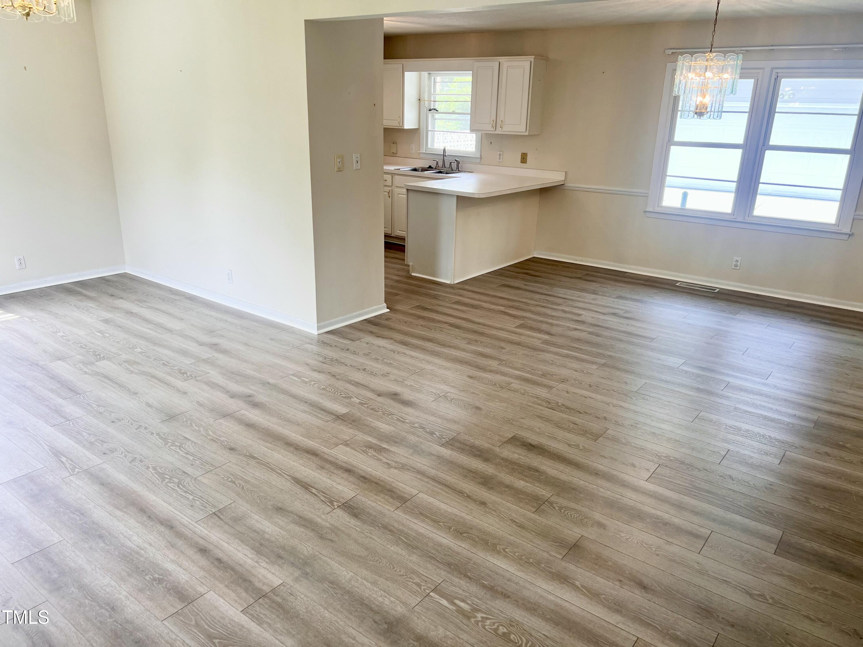 1517 Westchester Road Raleigh, NC 27610 - Photo 5 of 13 an empty room with wooden floor and windows