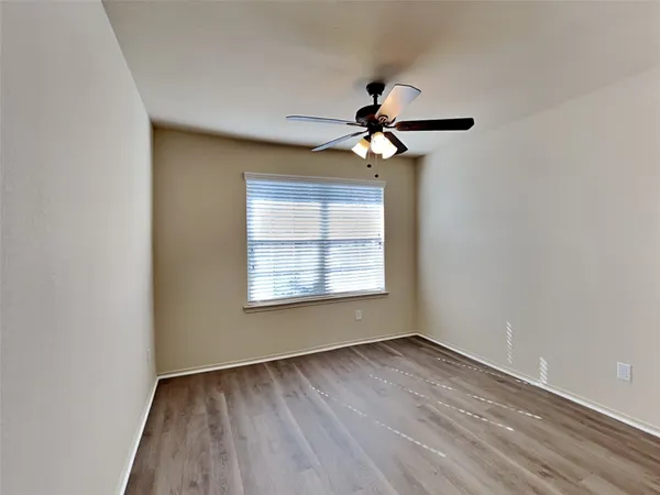 a view of an empty room with a window and a chandelier fan