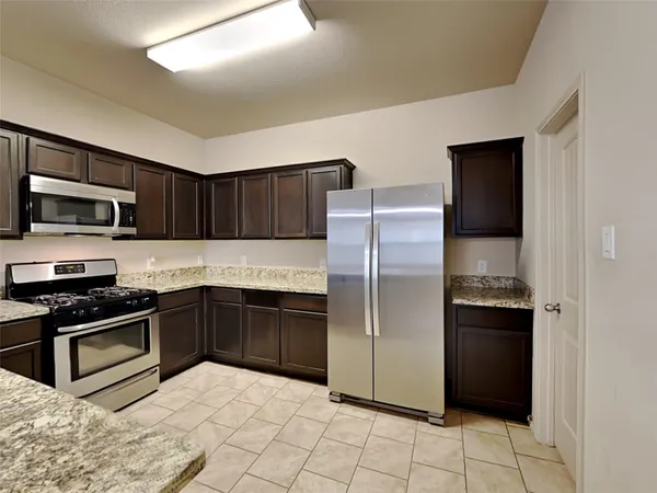 a kitchen with granite countertop a refrigerator and a stove top oven