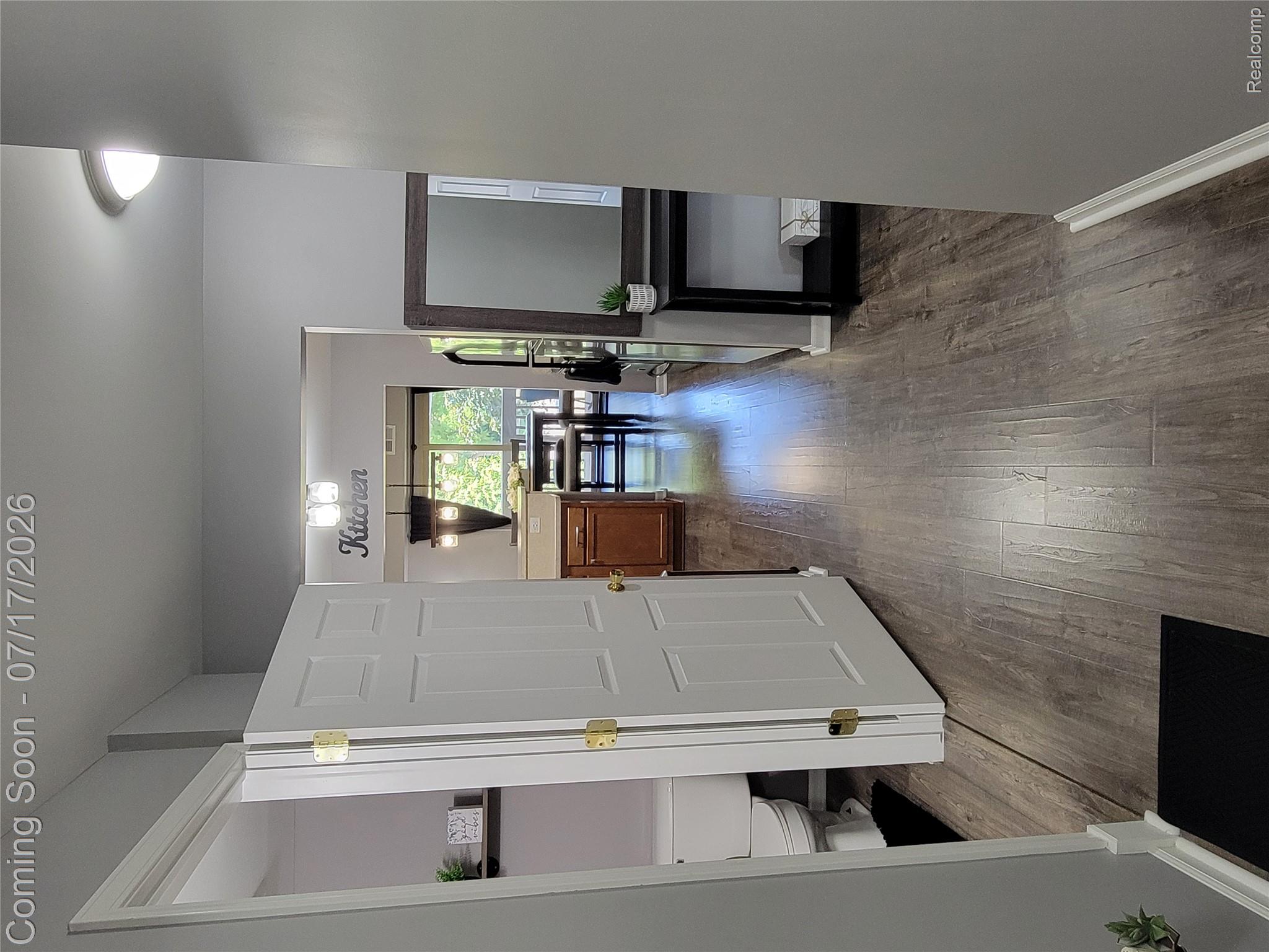 Hallway featuring wood-finish flooring, light gray wall paint, and white trim