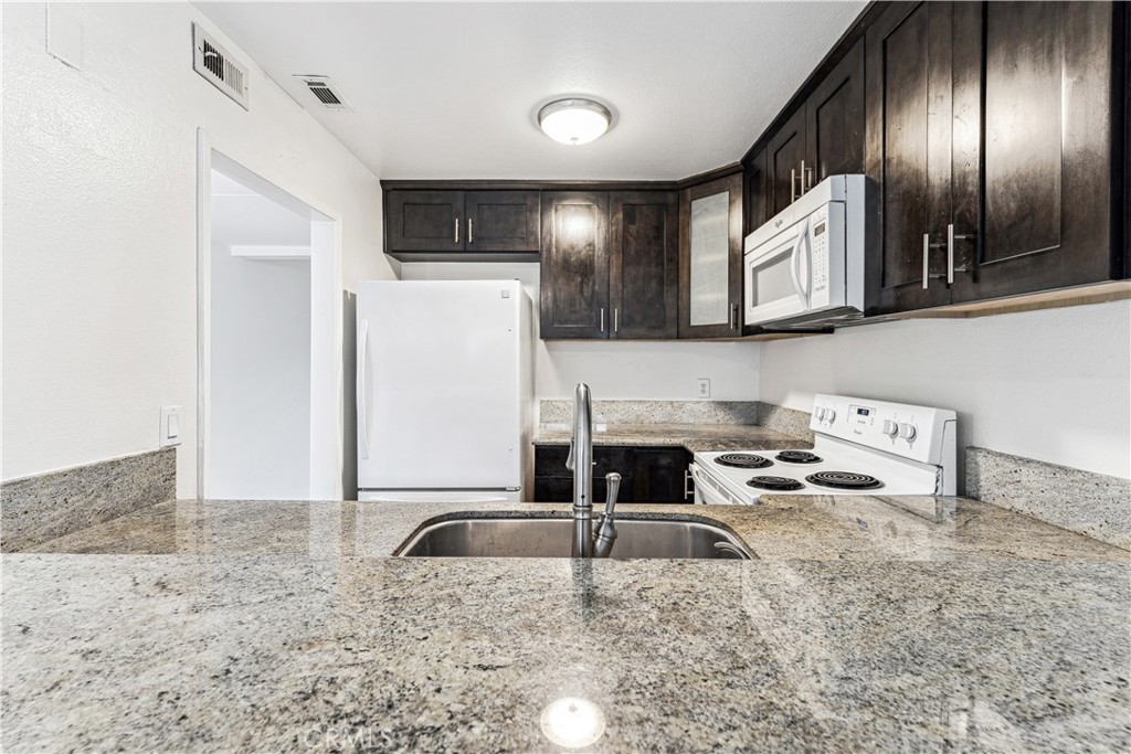 999 West Pine Street, Unit D Upland, CA 91786 - Photo 6 of 16 a kitchen with granite countertop a sink a stove and refrigerator