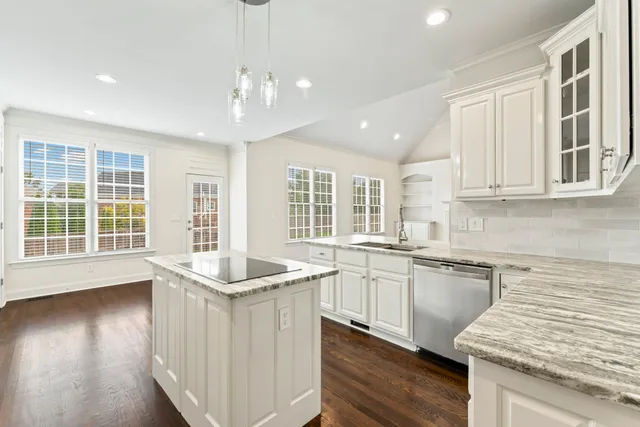 a white kitchen with stainless steel appliances granite countertop a sink dishwasher stove and white cabinets with wooden floor