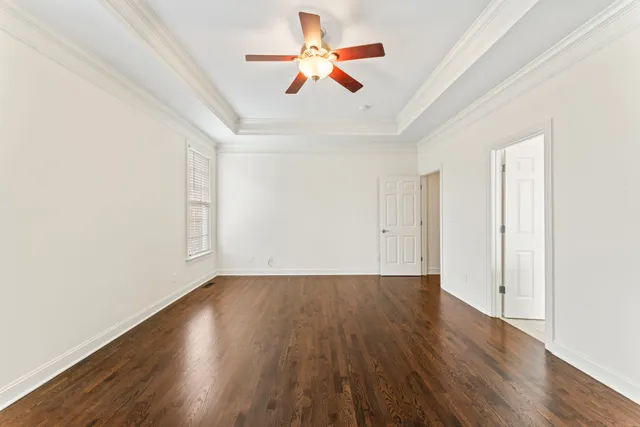 an empty room with wooden floor and a ceiling fan