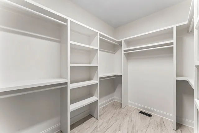 a view of an empty room with wooden floor and a ceiling fan