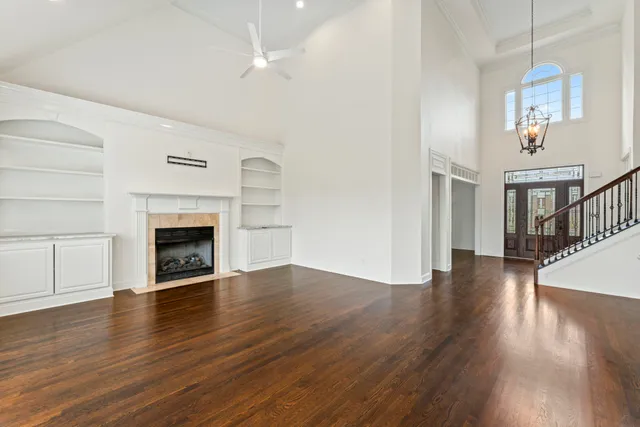 an empty room with wooden floor fireplace and windows