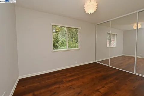 a view of an empty room with a window and wooden floor