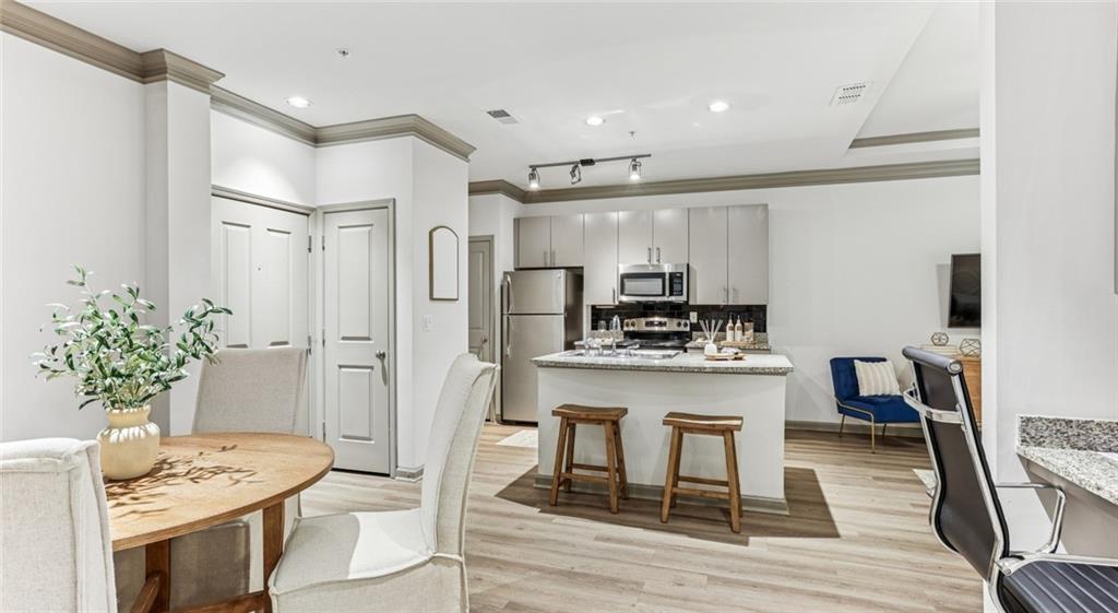 2910 Clairmont Road, Unit PLAN 1 Atlanta, GA 30329 - Photo 21 of 29 a kitchen with stainless steel appliances kitchen island granite countertop a dining table chairs and white cabinets