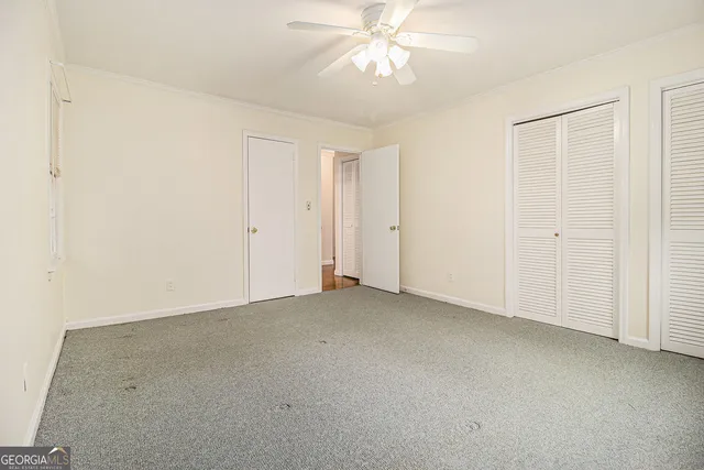 an empty room with a chandelier fan and closet area