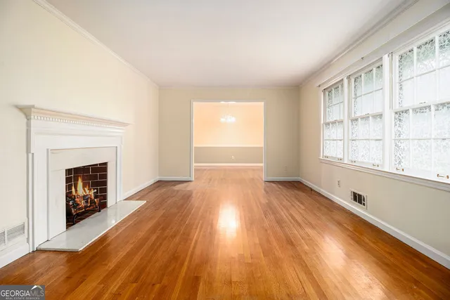 a view of an empty room with wooden floor fireplace and a window