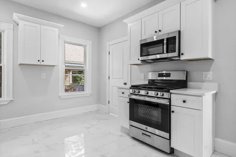 a kitchen with stainless steel appliances granite countertop white cabinets a stove top oven and a sink