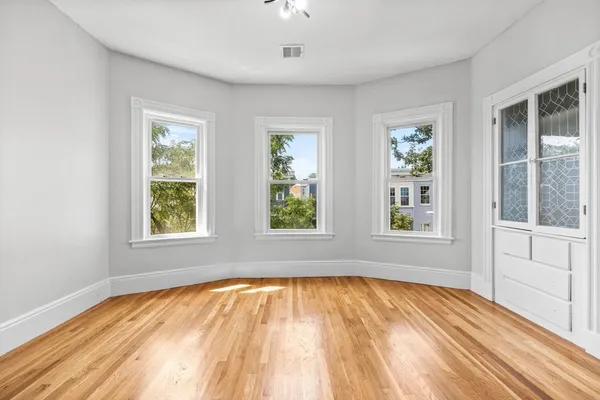 a view of empty room with wooden floor and fan