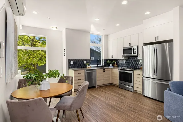 a kitchen with white cabinets stainless steel appliances and wooden floor