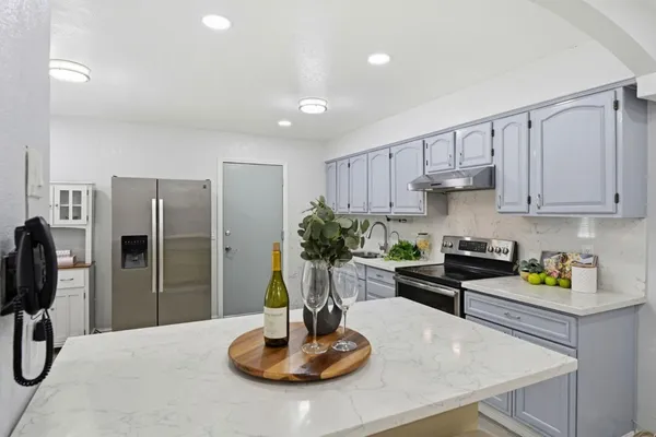 a kitchen with stainless steel appliances granite countertop a refrigerator a sink a stove and white cabinets