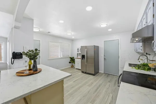 a kitchen with stainless steel appliances a dining table chairs and wooden floor