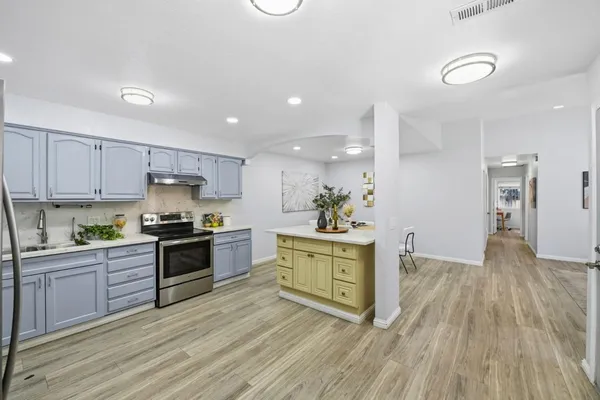 a kitchen with stainless steel appliances granite countertop a stove a sink dishwasher and a refrigerator with wooden floor