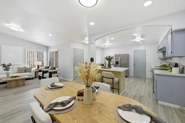a living room with furniture kitchen view and a wooden floor