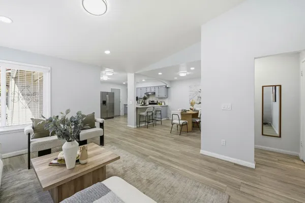 a living room with furniture kitchen view and a wooden floor