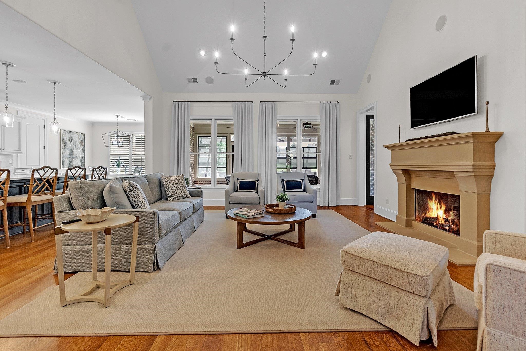 3246 North Hartwell Ridge Drive Collierville, TN 38017 - Photo 15 of 40 Spacious living area featuring high vaulted ceilings, rich hardwood flooring, a substantial fireplace with a mantel, and an elegant chandelier