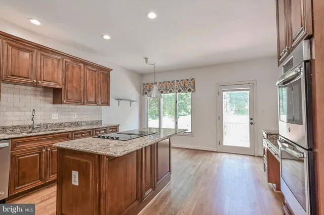 a kitchen with stainless steel appliances granite countertop a sink a stove a refrigerator and cabinets