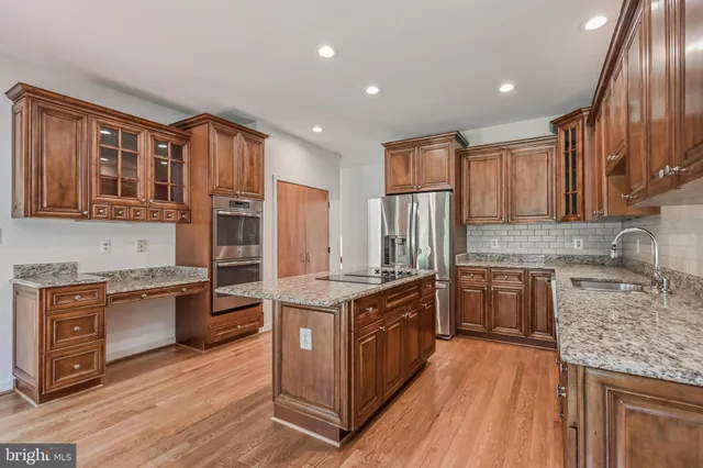 a kitchen with stainless steel appliances granite countertop wooden cabinets a refrigerator and a stove