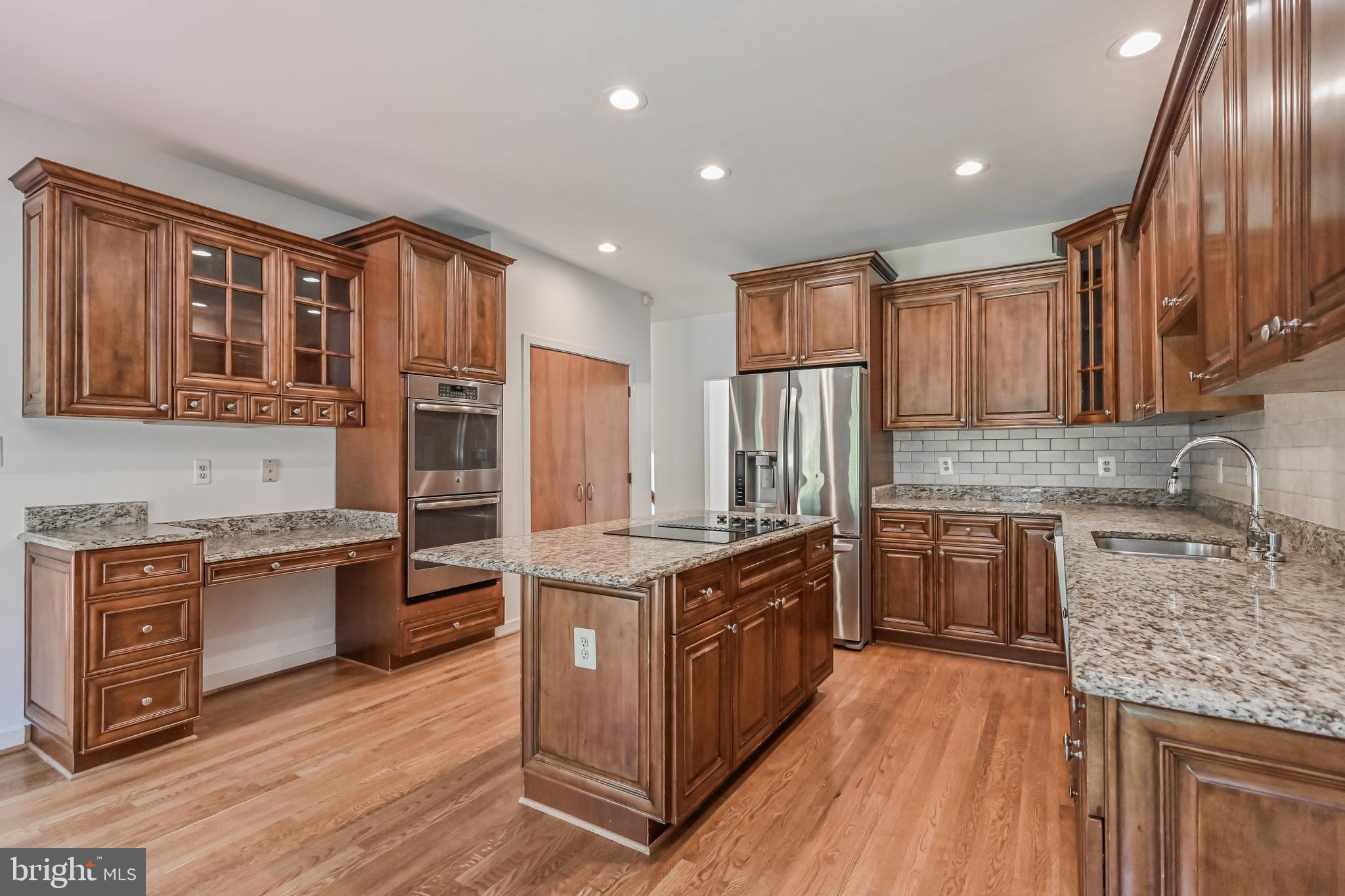 445 Springvale Road Great Falls, VA 22066 - Photo 10 of 62 a kitchen with stainless steel appliances granite countertop a stove top oven a refrigerator a sink and dishwasher with wooden floor