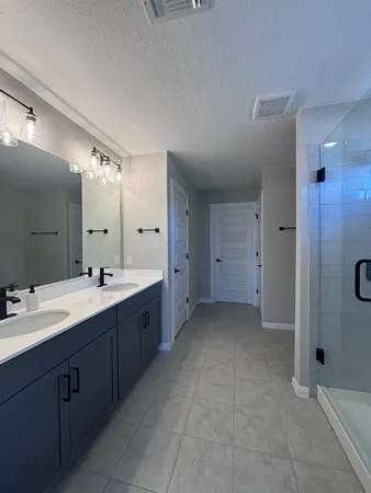 a spacious bathroom with a double vanity sink a large mirror and shower