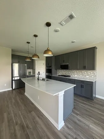 a large kitchen with stainless steel appliances a large counter top a sink and a stove