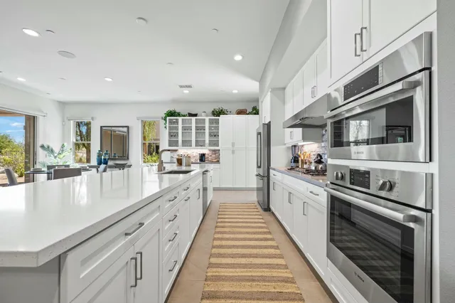a large white kitchen with a large window and furniture