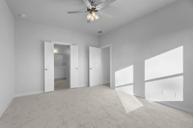 an empty room with chandelier fan and windows