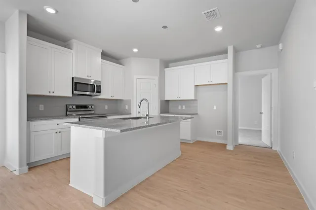 a view of a kitchen with a stove cabinets a ceiling fan and wooden floor