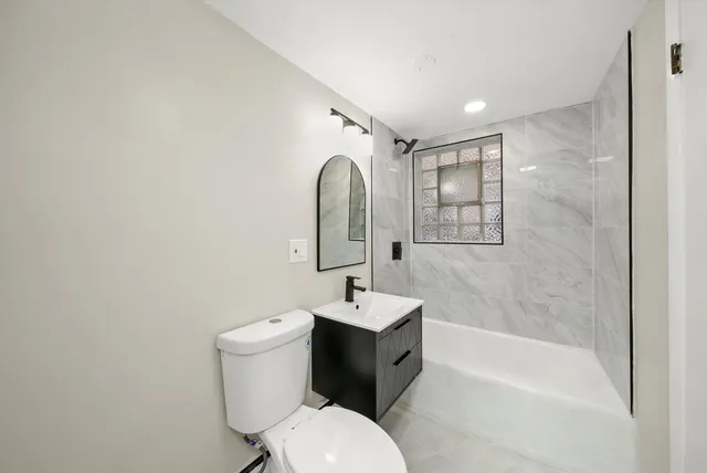 a bathroom with a bathtub shower sink mirror and toilet