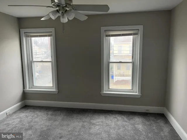 an empty room with a window and a fan
