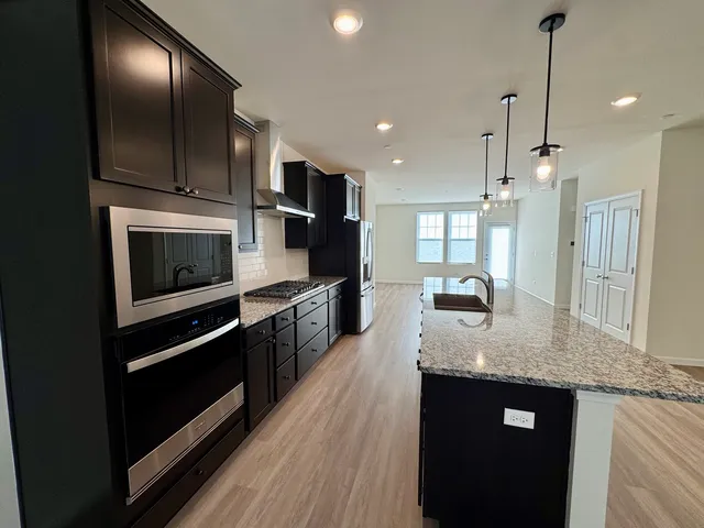 a kitchen with stainless steel appliances granite countertop a stove a sink and a microwave