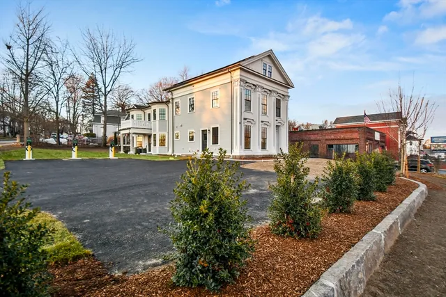 a view of a white house next to a yard with big trees