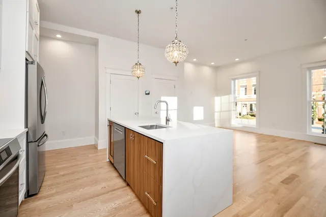 a large kitchen with stainless steel appliances a large counter top space a sink a refrigerator and a window