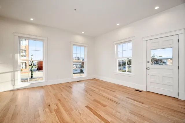an empty room with wooden floor and windows