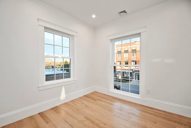 an empty room with wooden floor and windows
