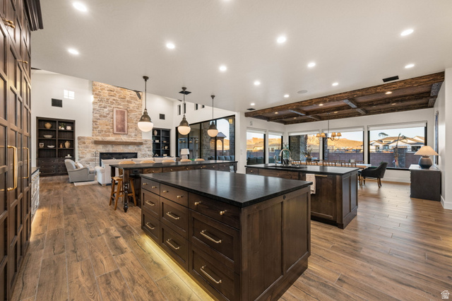 4871 South Homestead Way Washington, UT 84780 - Photo 148 of 151 Kitchen featuring open floor plan, dark wood finish cabinetry, a fireplace, pendant lighting, and light wood finished floors