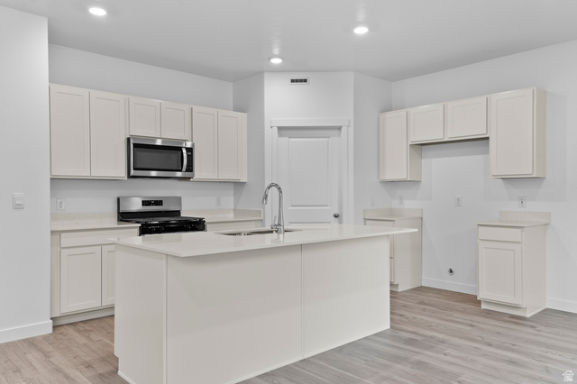 2829 North 710 West, Unit 15 Logan, UT 84321 - Photo 12 of 23 Modern kitchen featuring light cabinetry, a central island with a sink, stainless steel appliances, and wood-finish flooring