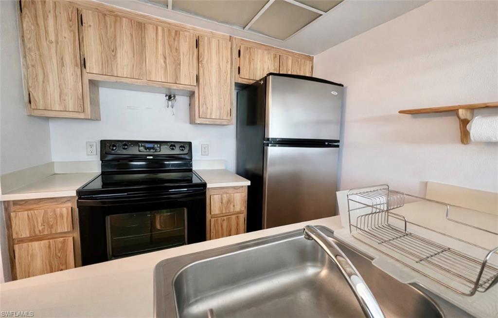 4293 27th Court Southwest, Unit 203 Naples, FL 34116 - Photo 14 of 22 a kitchen with stainless steel appliances granite countertop a refrigerator sink and stove