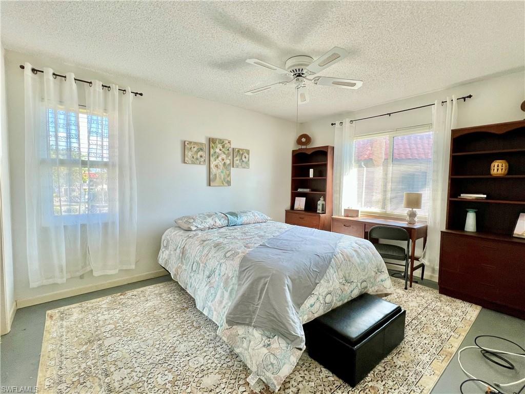 4293 27th Court Southwest, Unit 203 Naples, FL 34116 - Photo 18 of 26 a bedroom with a bed a dresser and a large window
