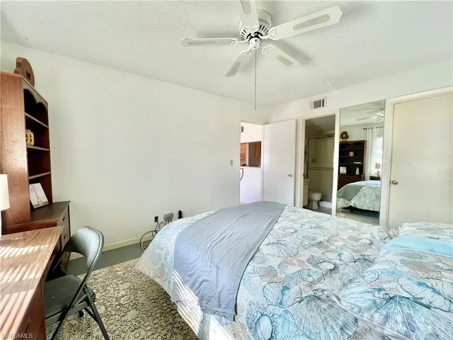 a spacious bedroom with a bed a couch and a chandelier