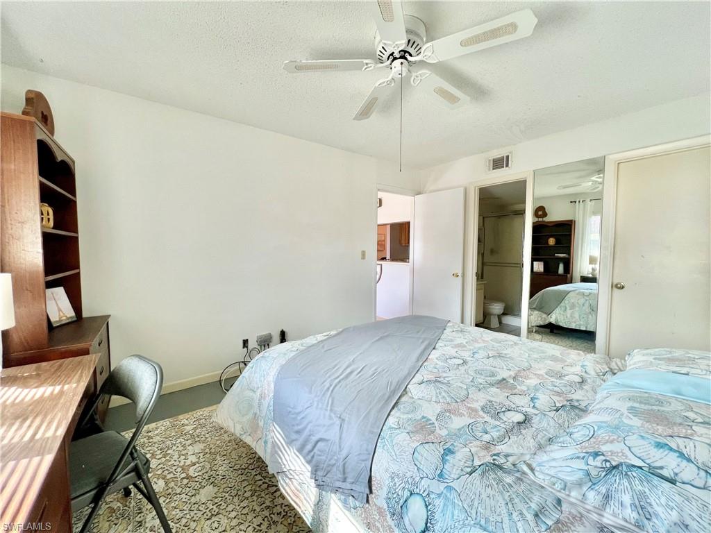 4293 27th Court Southwest, Unit 203 Naples, FL 34116 - Photo 20 of 26 a spacious bedroom with a bed a couch and a chandelier